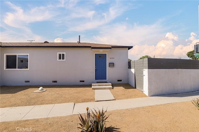 view of front facade featuring crawl space, stucco siding, a gate, and fence