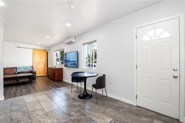 foyer entrance featuring a barn door, a wall unit AC, recessed lighting, and baseboards