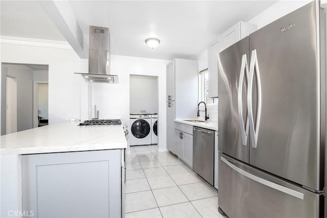 kitchen featuring light stone counters, a sink, appliances with stainless steel finishes, island range hood, and washer and dryer