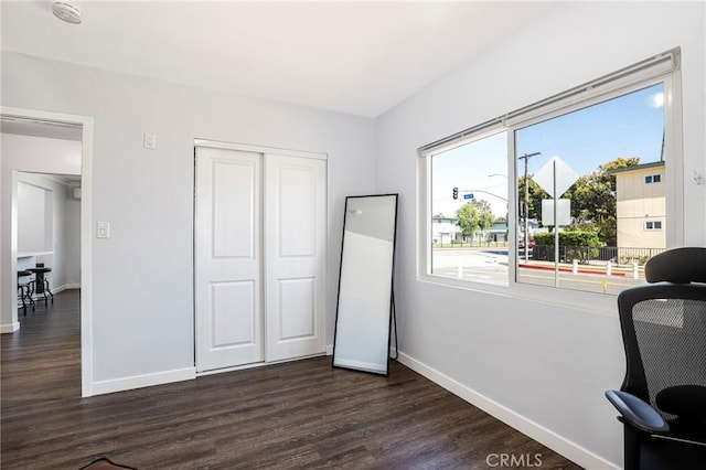 interior space featuring a closet, baseboards, and dark wood-type flooring