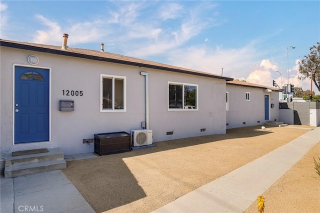 rear view of house with crawl space, stucco siding, ac unit, and fence
