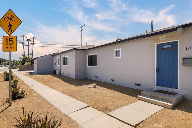 view of property exterior with stucco siding, central AC, and crawl space