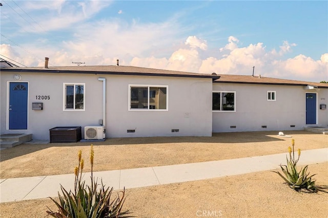 rear view of property with stucco siding, ac unit, and crawl space