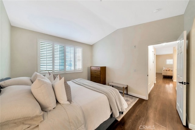 bedroom featuring baseboards, dark wood finished floors, and vaulted ceiling