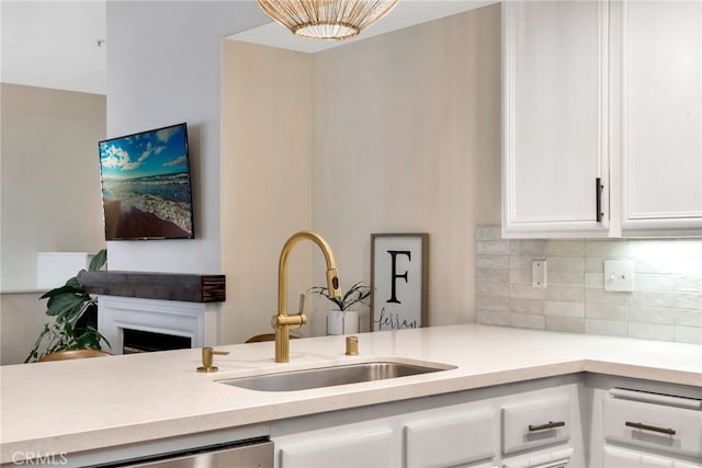 kitchen featuring a sink, decorative backsplash, white cabinets, and light countertops