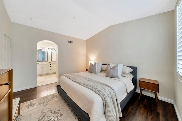 bedroom featuring visible vents, arched walkways, wood finished floors, baseboards, and lofted ceiling