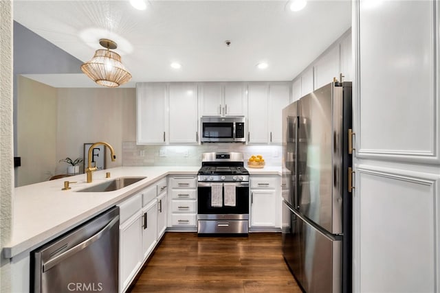 kitchen with backsplash, dark wood-style flooring, appliances with stainless steel finishes, a sink, and light countertops