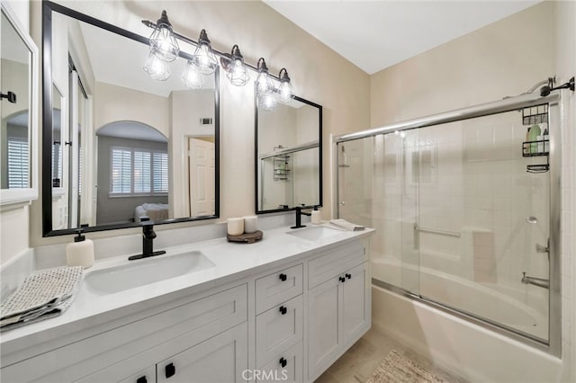 full bath with double vanity, a sink, enclosed tub / shower combo, and ensuite bath