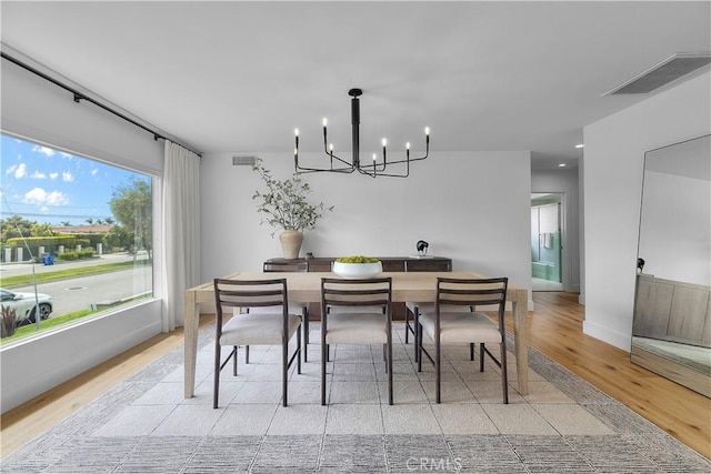 dining area with a chandelier, visible vents, light wood-style flooring, and baseboards