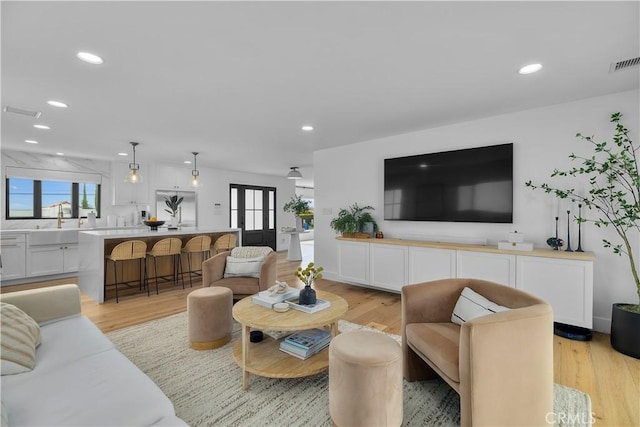 living area featuring visible vents, light wood-type flooring, and recessed lighting