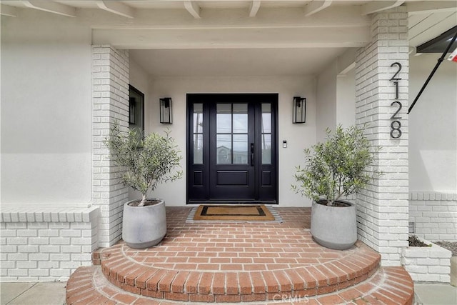 doorway to property with stucco siding and brick siding