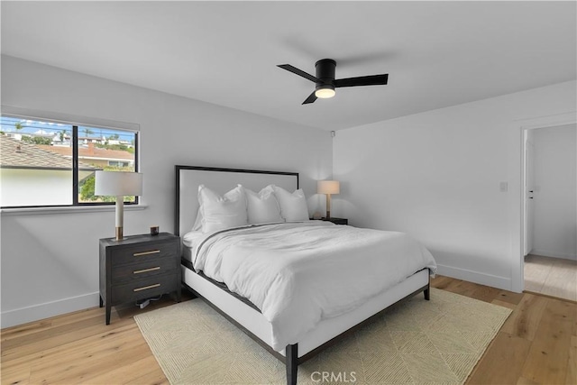 bedroom with baseboards, a ceiling fan, and light wood-style floors