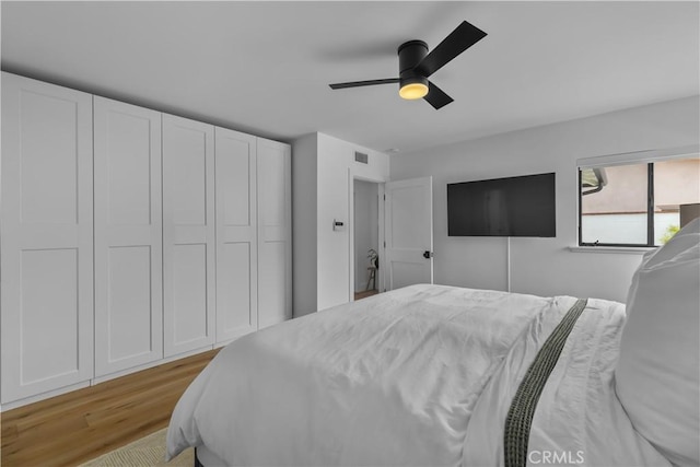 bedroom featuring a ceiling fan, visible vents, and light wood-style flooring