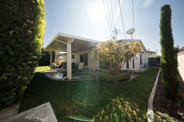 back of property with a lawn, fence, a patio area, and stucco siding