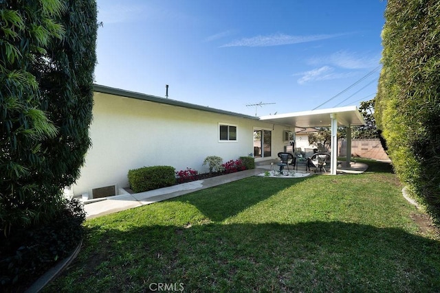 rear view of property with a lawn, a patio, and stucco siding