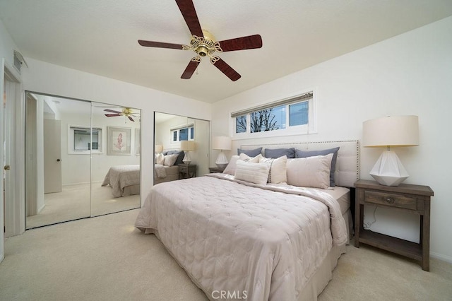 bedroom with visible vents, a ceiling fan, and light colored carpet