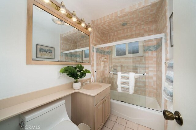 full bathroom featuring tile patterned floors, toilet, combined bath / shower with glass door, and vanity