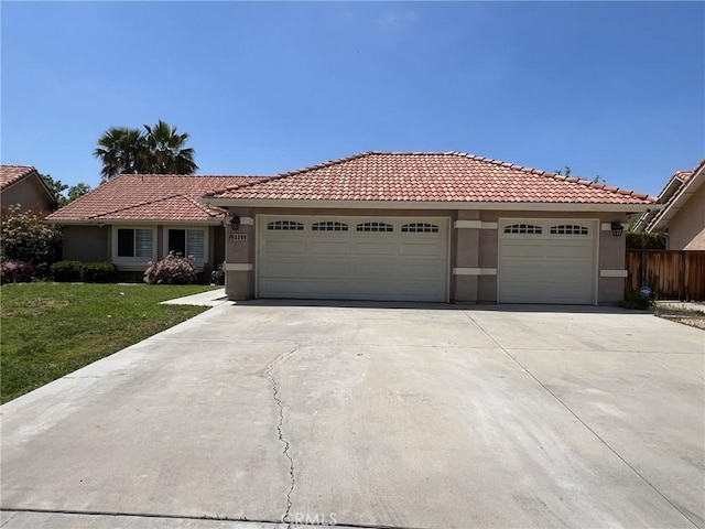 ranch-style home featuring a garage, driveway, a tile roof, and stucco siding