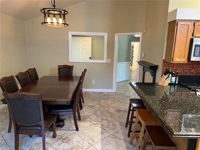 dining space featuring baseboards, high vaulted ceiling, and an inviting chandelier