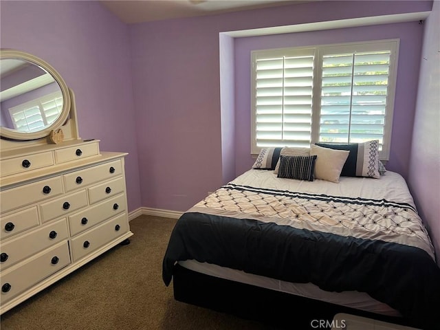 bedroom featuring baseboards and dark carpet