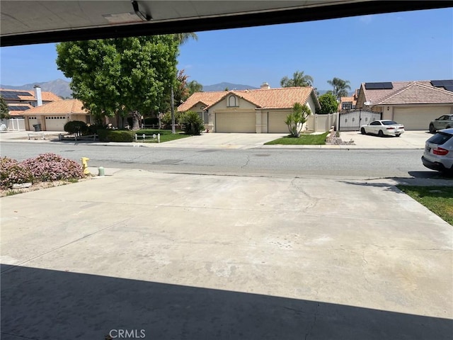 view of road with concrete driveway, a residential view, and a mountain view