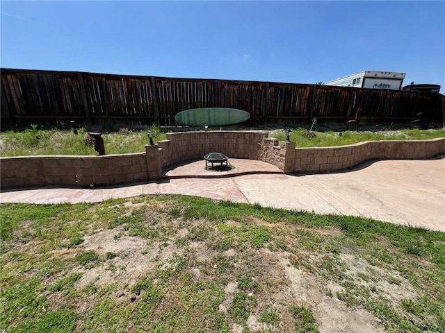 view of yard featuring a patio, a fenced backyard, and a fire pit