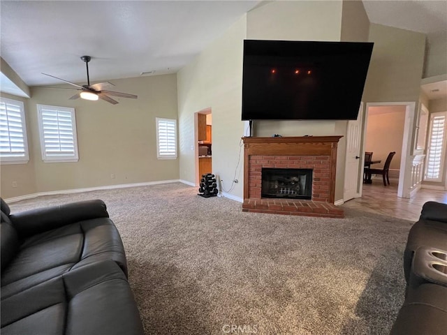 living room featuring a brick fireplace, baseboards, high vaulted ceiling, a ceiling fan, and carpet