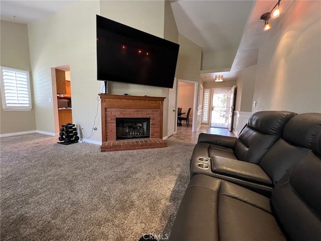 carpeted living room with high vaulted ceiling, baseboards, and a fireplace