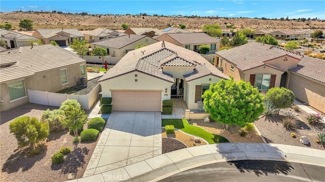 view of front of home featuring a residential view, fence, a garage, stucco siding, and driveway