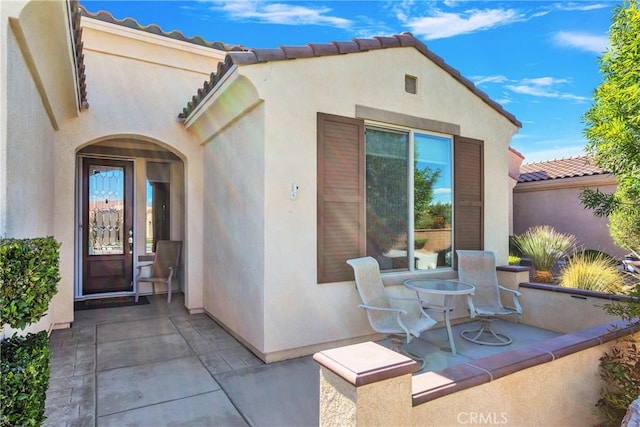 doorway to property featuring a patio, stucco siding, and a tiled roof