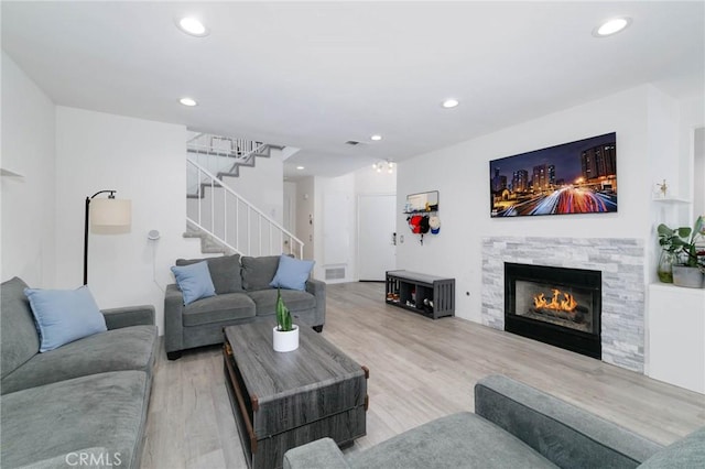 living room featuring recessed lighting, stairs, wood finished floors, and a stone fireplace