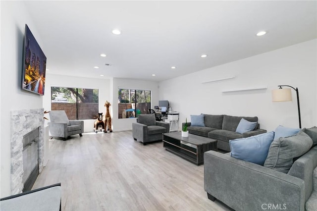 living room featuring recessed lighting, a glass covered fireplace, and light wood-type flooring