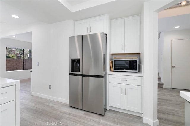 kitchen featuring appliances with stainless steel finishes, baseboards, light wood-type flooring, and white cabinetry