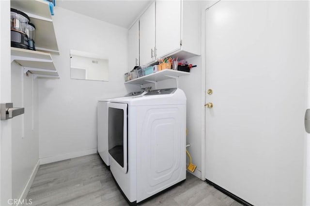 laundry room with cabinet space, baseboards, washer and clothes dryer, and light wood-type flooring