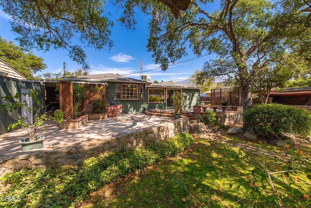 rear view of property featuring a fenced backyard, a sunroom, and a patio area