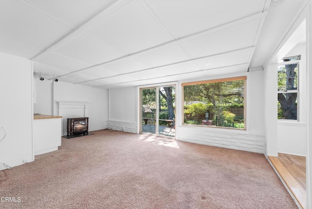 unfurnished living room featuring a wood stove and light carpet