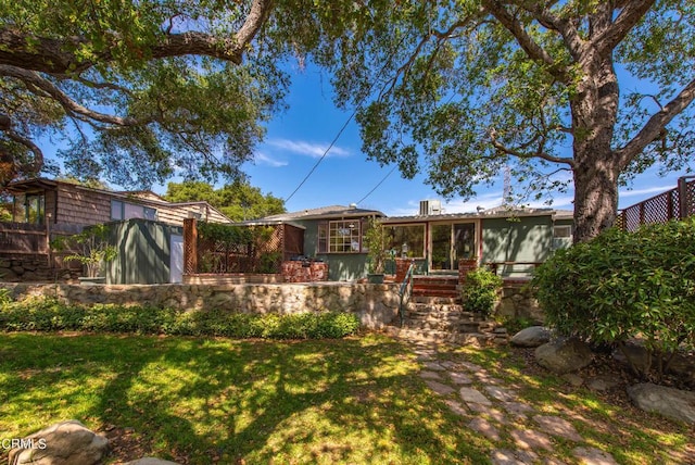 back of house featuring fence, a sunroom, and a lawn