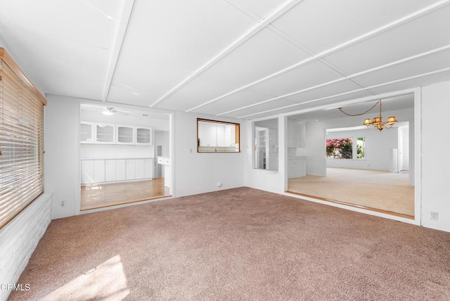 unfurnished living room featuring ceiling fan with notable chandelier and carpet