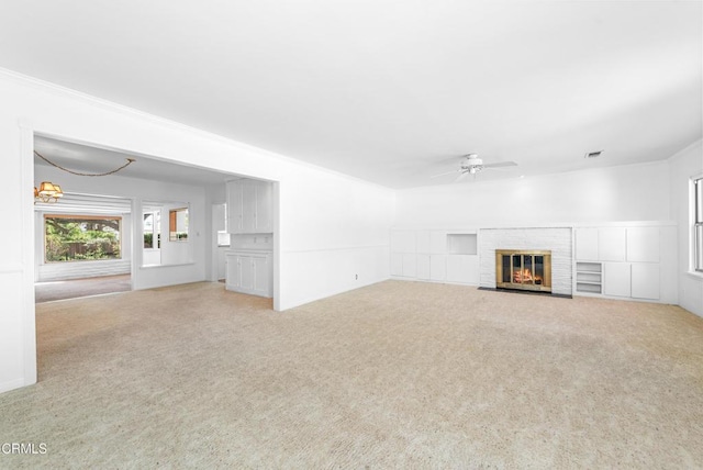 unfurnished living room with a brick fireplace, visible vents, a ceiling fan, and carpet floors