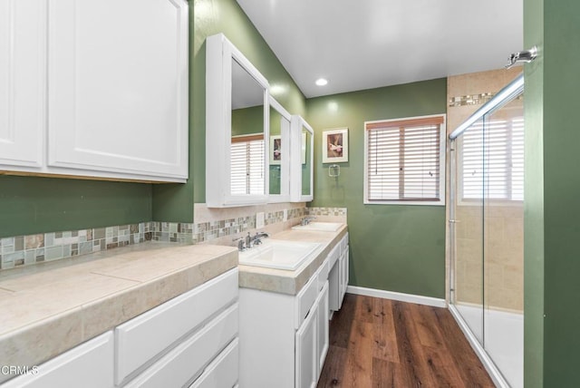 full bath featuring tasteful backsplash, wood finished floors, a shower stall, and a sink