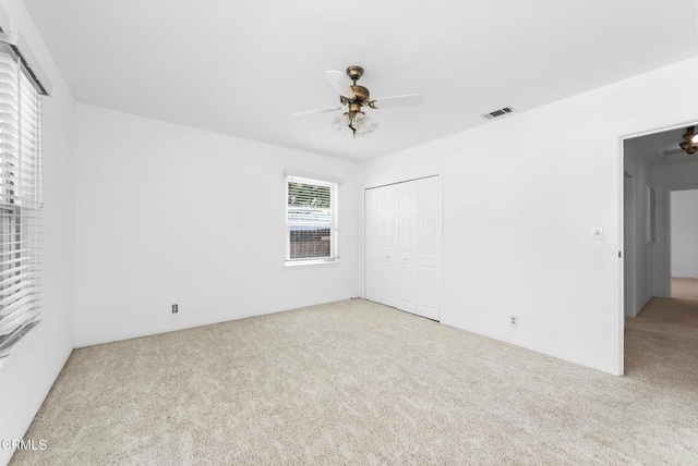 unfurnished bedroom featuring a closet, carpet flooring, a ceiling fan, and visible vents