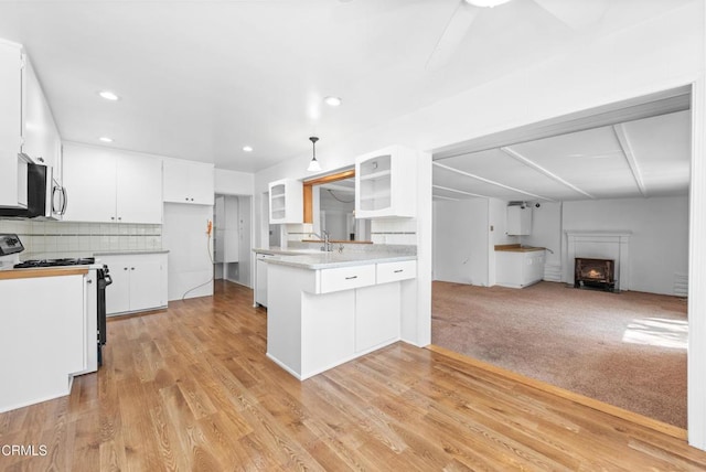 kitchen featuring stainless steel microwave, white cabinetry, black gas stove, light countertops, and open floor plan