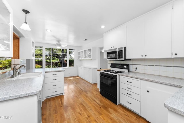 kitchen featuring stainless steel microwave, a sink, ceiling fan, light wood-style floors, and gas stove