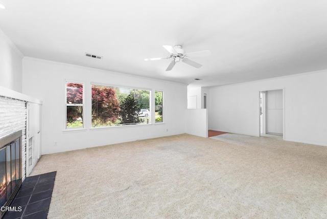 unfurnished living room with ornamental molding, visible vents, a fireplace with flush hearth, and carpet