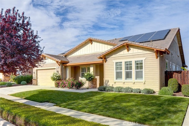 view of front facade with board and batten siding, fence, a garage, roof mounted solar panels, and a front lawn