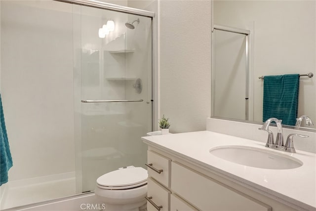 bathroom featuring toilet, a shower stall, and vanity