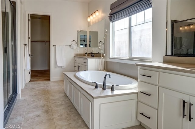 bathroom featuring vanity, a bath, tile patterned floors, a stall shower, and a spacious closet