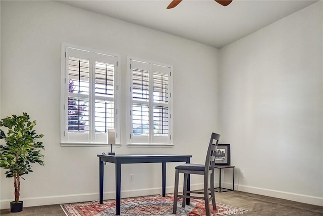carpeted office space with ceiling fan and baseboards