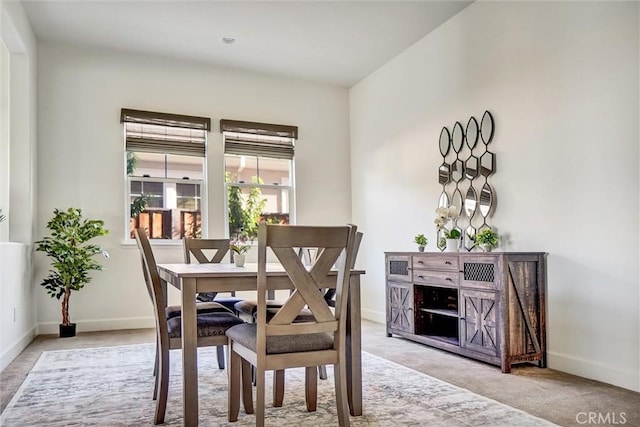 dining area featuring light carpet and baseboards