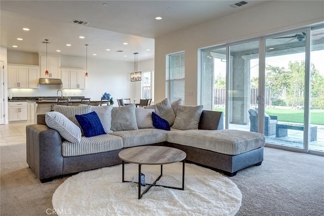 living area featuring visible vents, recessed lighting, and light carpet